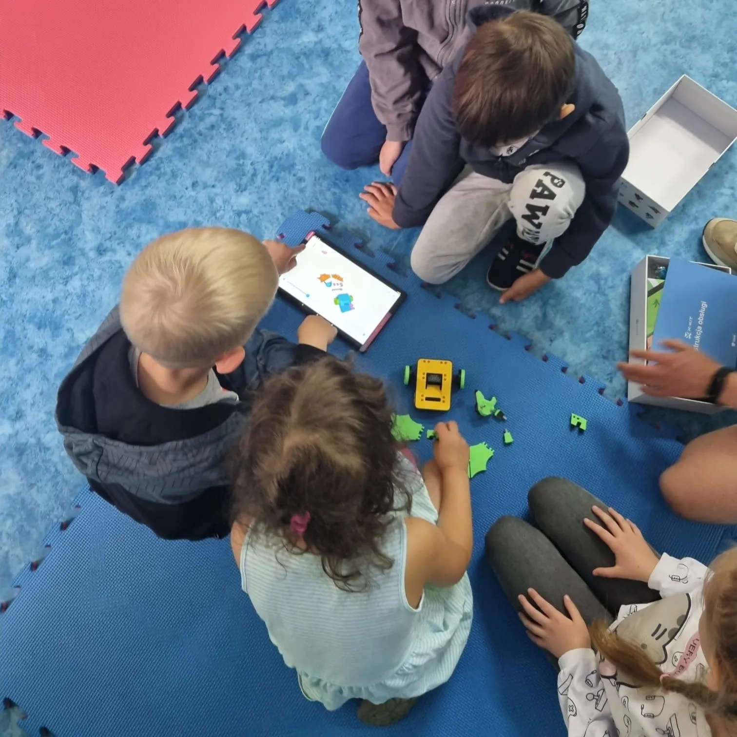 Young children building and driving a robot on the floor