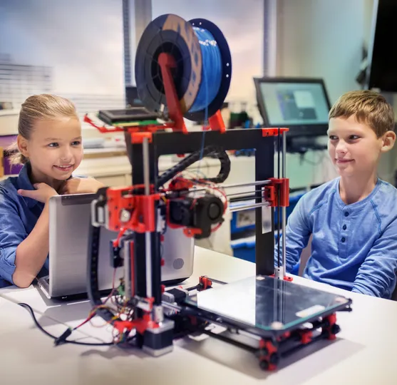 Children looking closely at a 3D printer